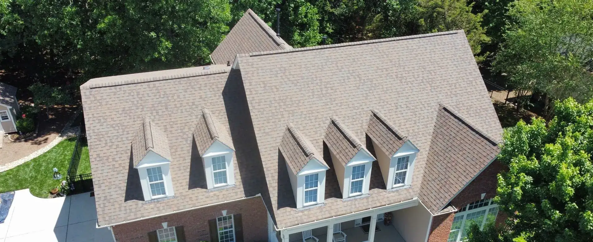 Gray shingle roof with three dormers and a brick chimney