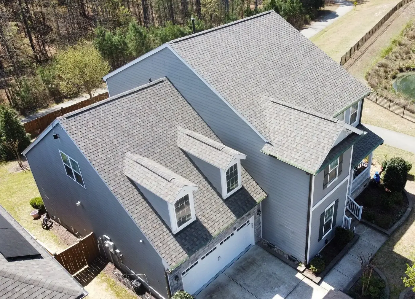 Aerial view of a two-story home with a gray shingle roof and dormers