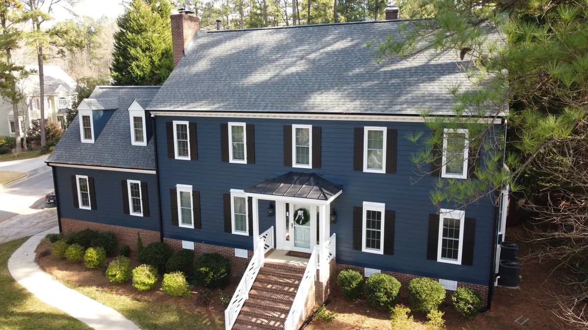 Colonial-style home painted navy with white trim and a brick front stoop